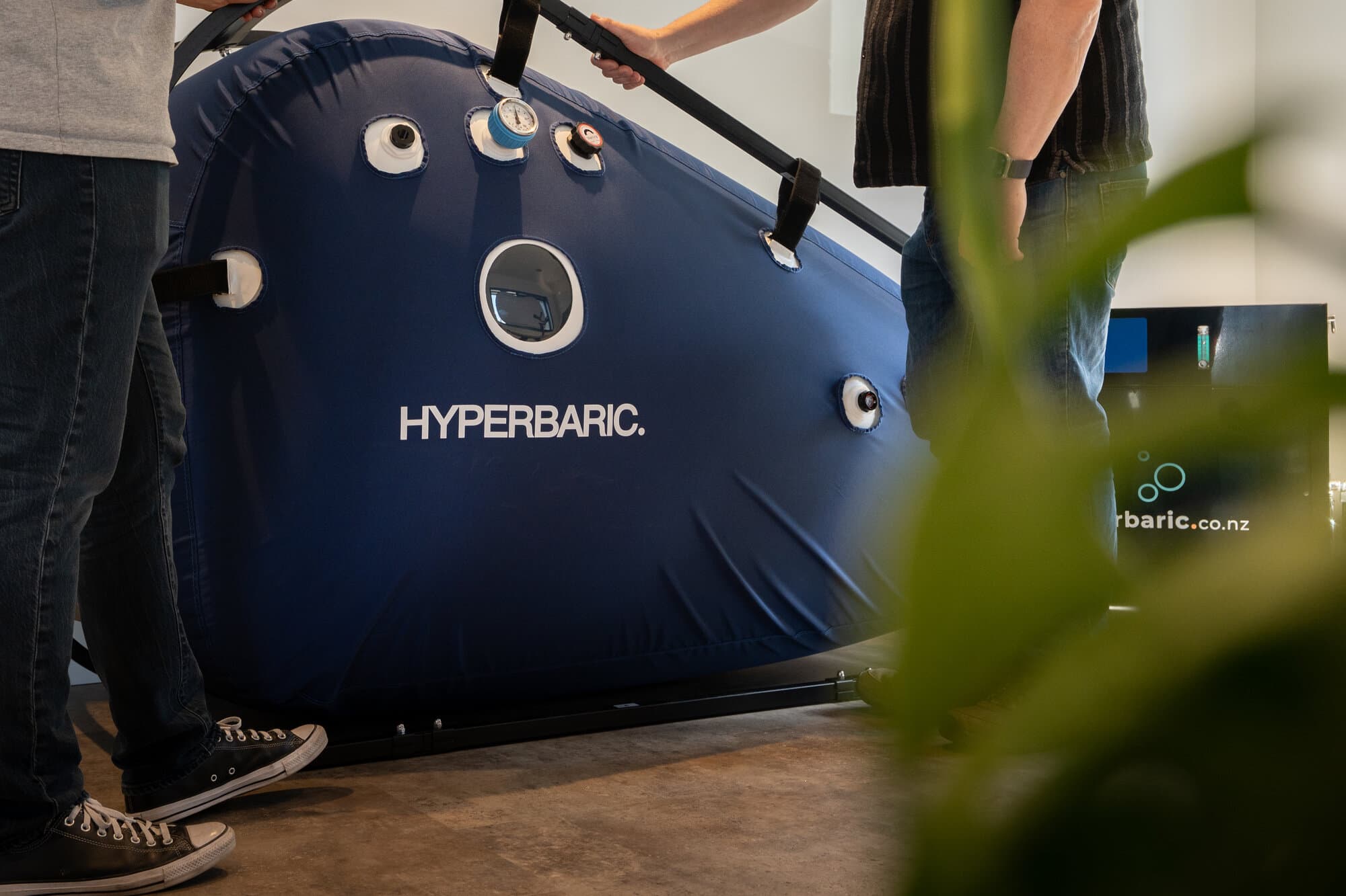 Callum and a colleague standing with the full hyperbaric chamber setup in the showroom